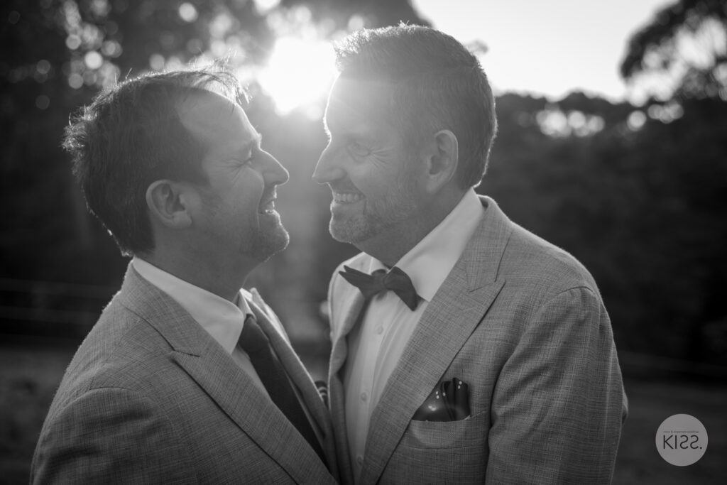 Two grooms kissing in black and white