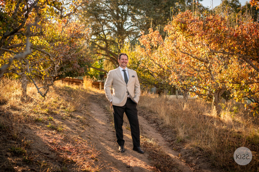 A groom posing among autumn trees