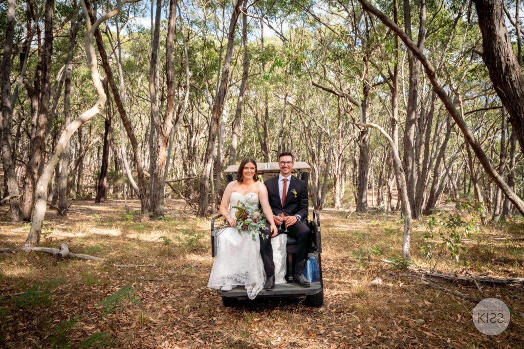 A wedding couple posing together on a forest path