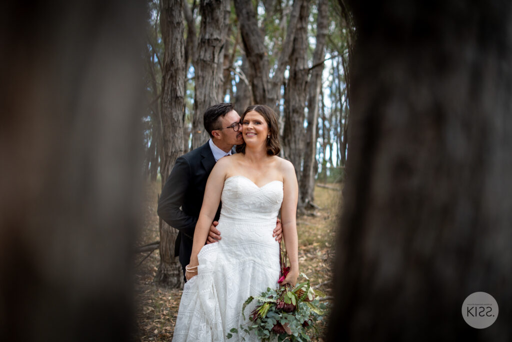 A wedding couple embracing among forest trees