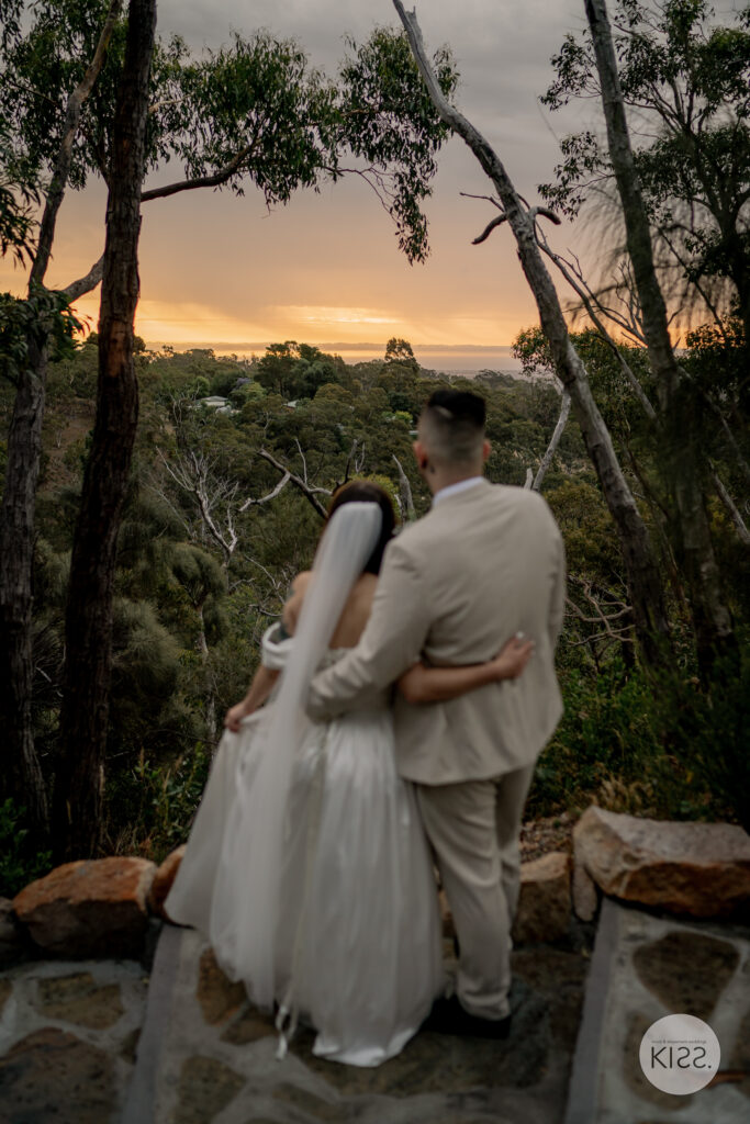 A wedding couple embracing among trees at dusk