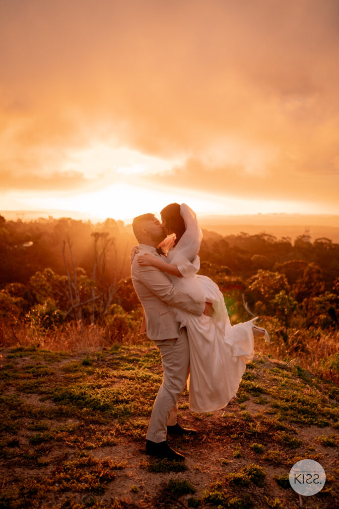 A wedding couple embracing against a glowing sunset
