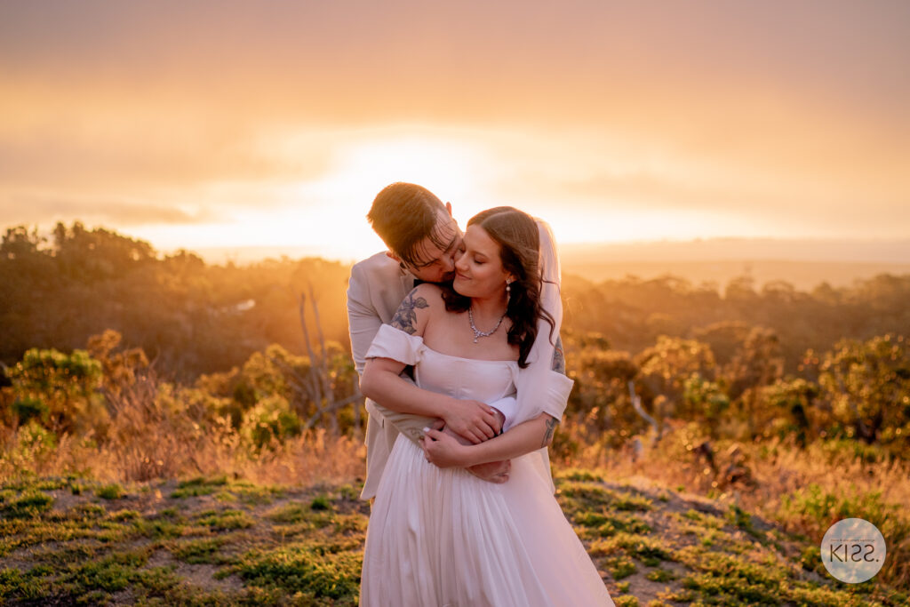 A wedding couple kissing at sunset