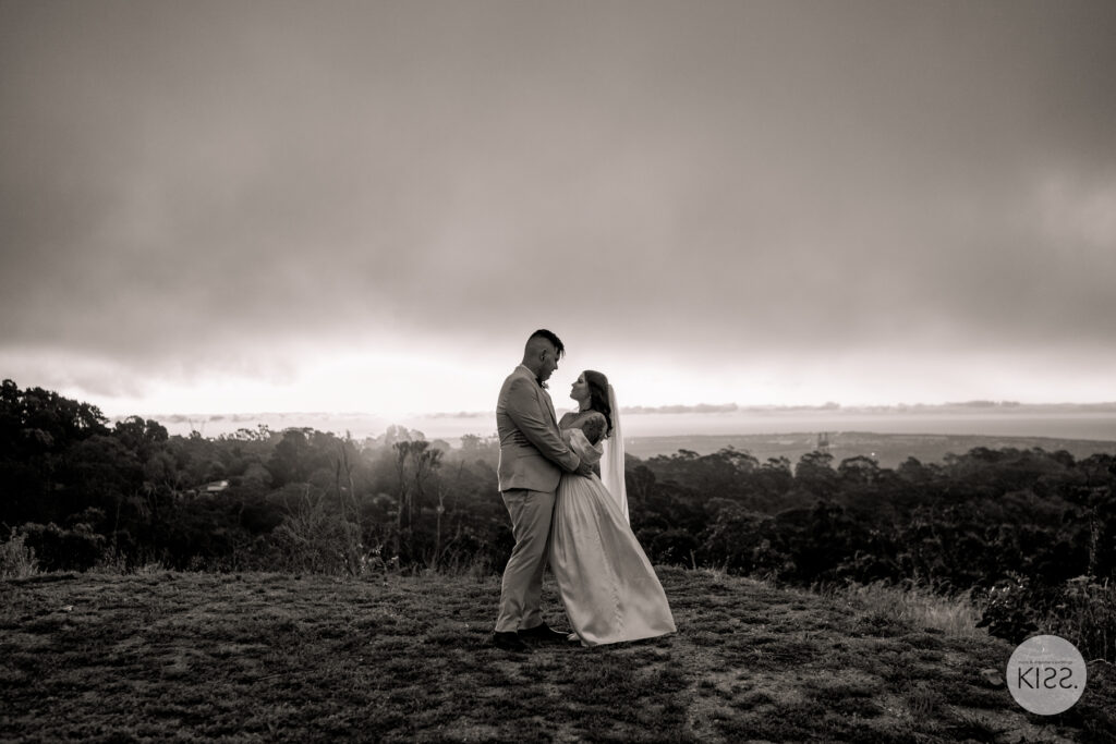A wedding couple embracing on a hill in black and white