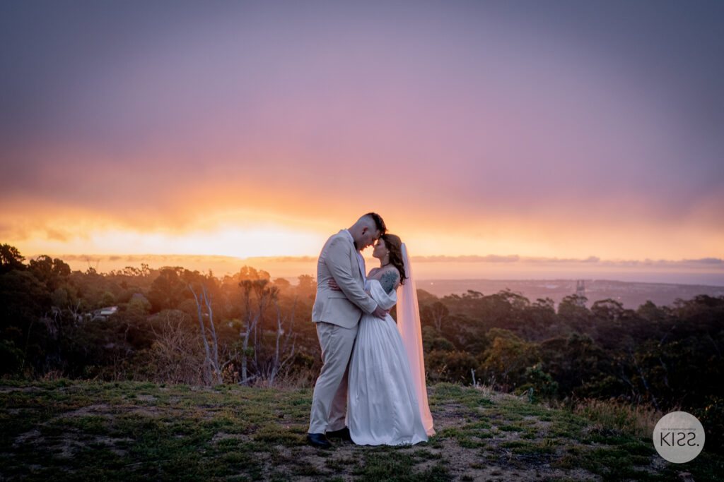 A wedding couple embracing beneath a colourful sunset at TOTOKA