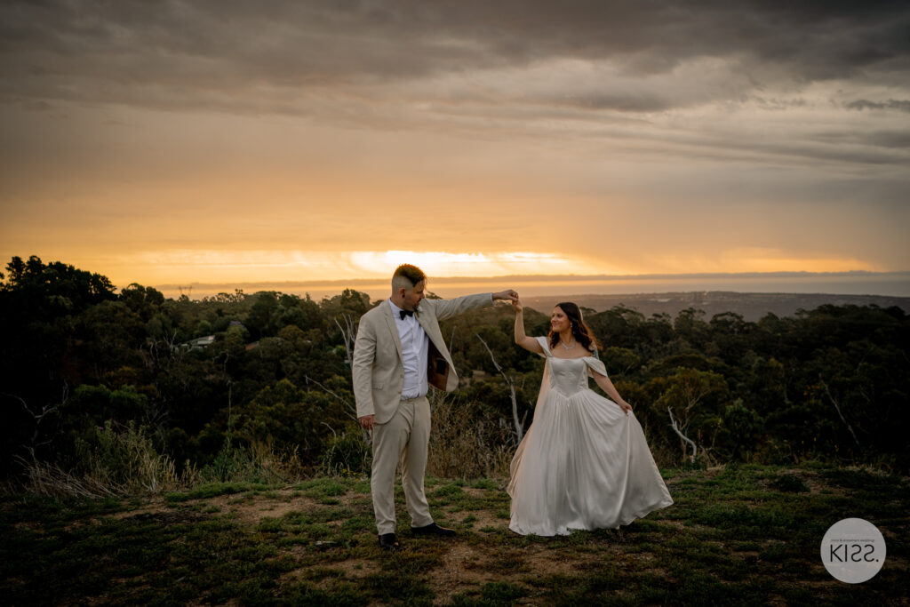 A groom twirling his bride at sunset