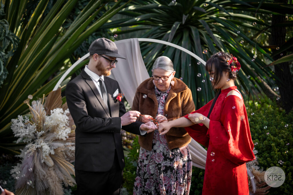 A couple taking part in a red string wedding ceremony