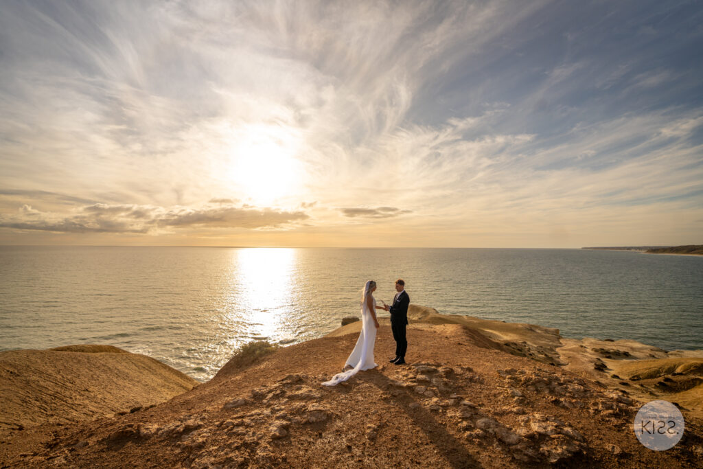 A couple exchanging vows on a coastal clifftop at sunset