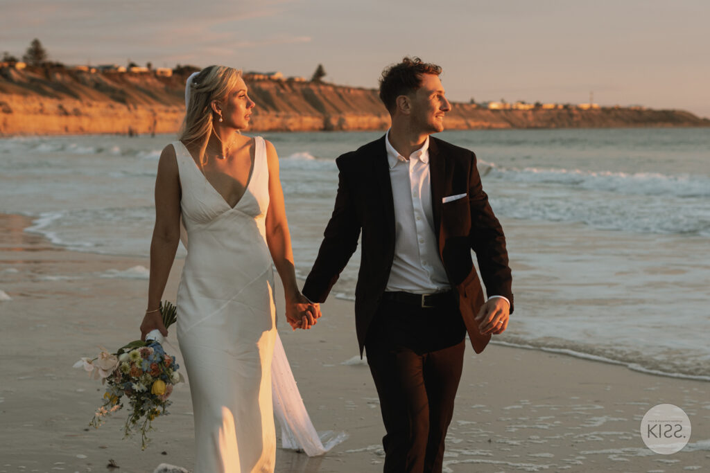 Bride and groom walking along the sand at Port Willunga