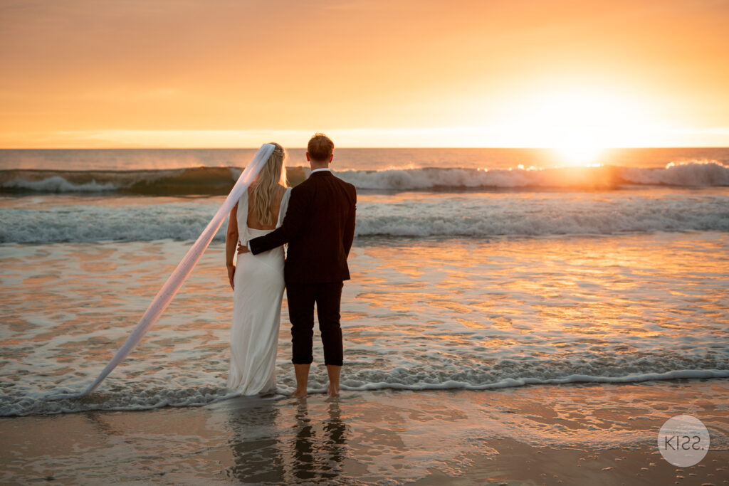 A wedding couple watching the sunset from the beach