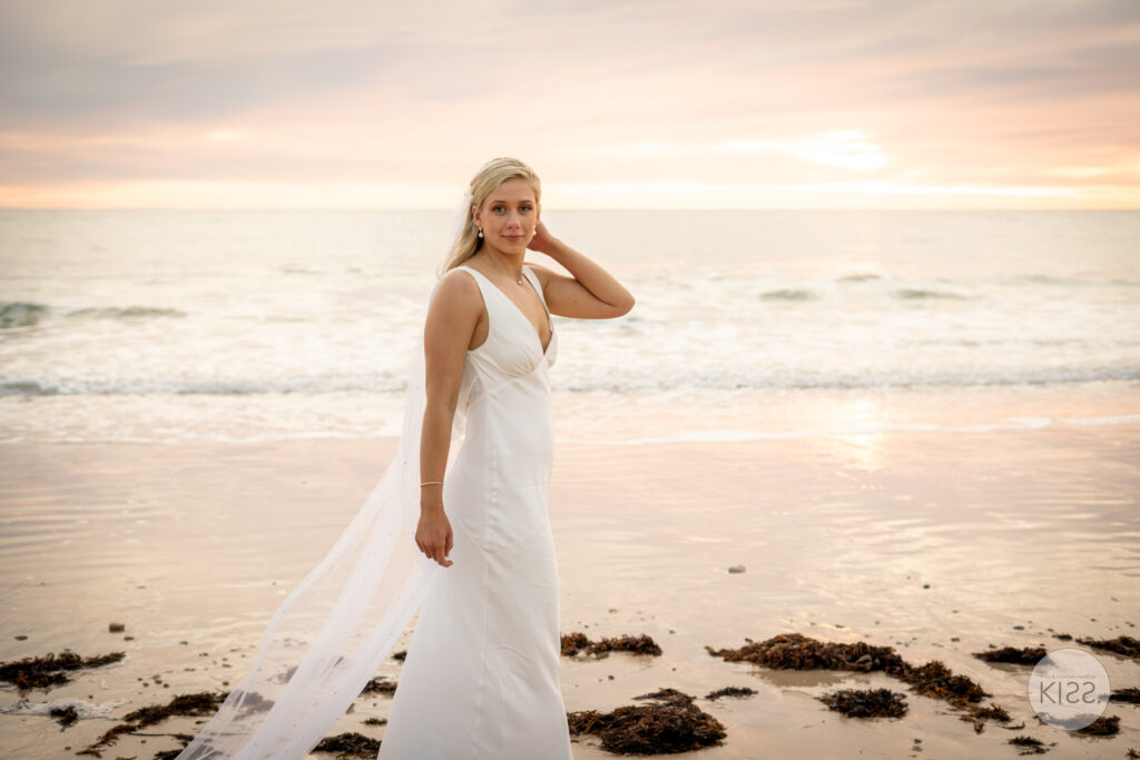 A bride standing on the beach at sunset
