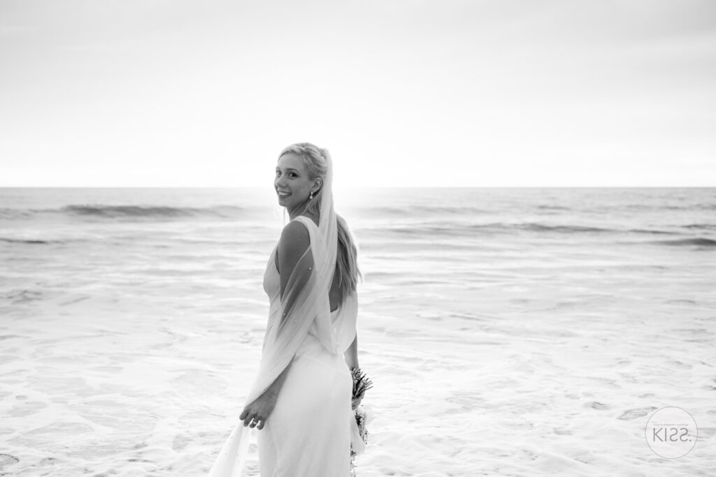 A bride looking back beside the sea in black and white