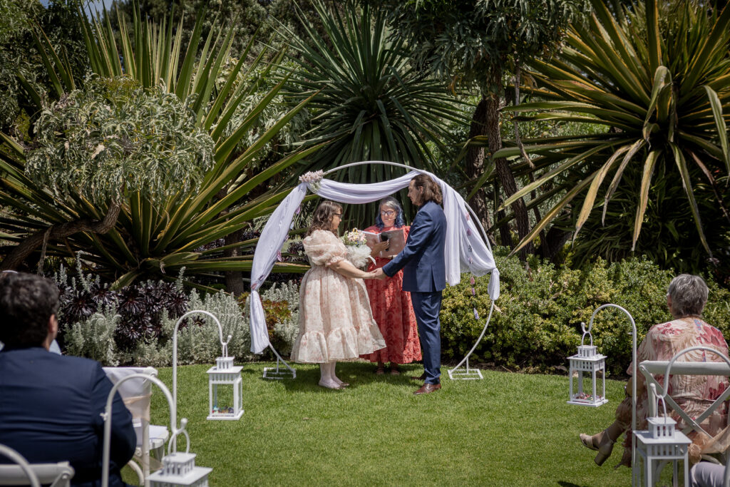 A garden wedding ceremony beneath a circular floral arbour