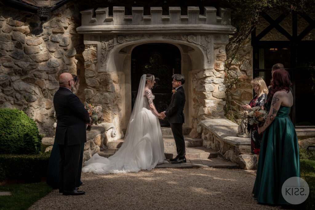 A wedding ceremony beneath the stone entrance at Thorngrove Manor