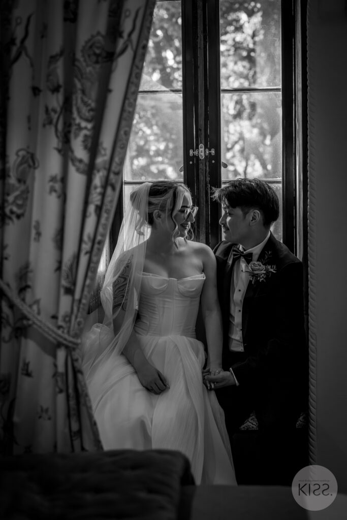 A wedding couple beside a window at Thorngrove Manor in black and white