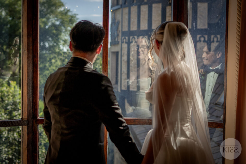A wedding couple standing beside a stained-glass window at Thorngrove Manor