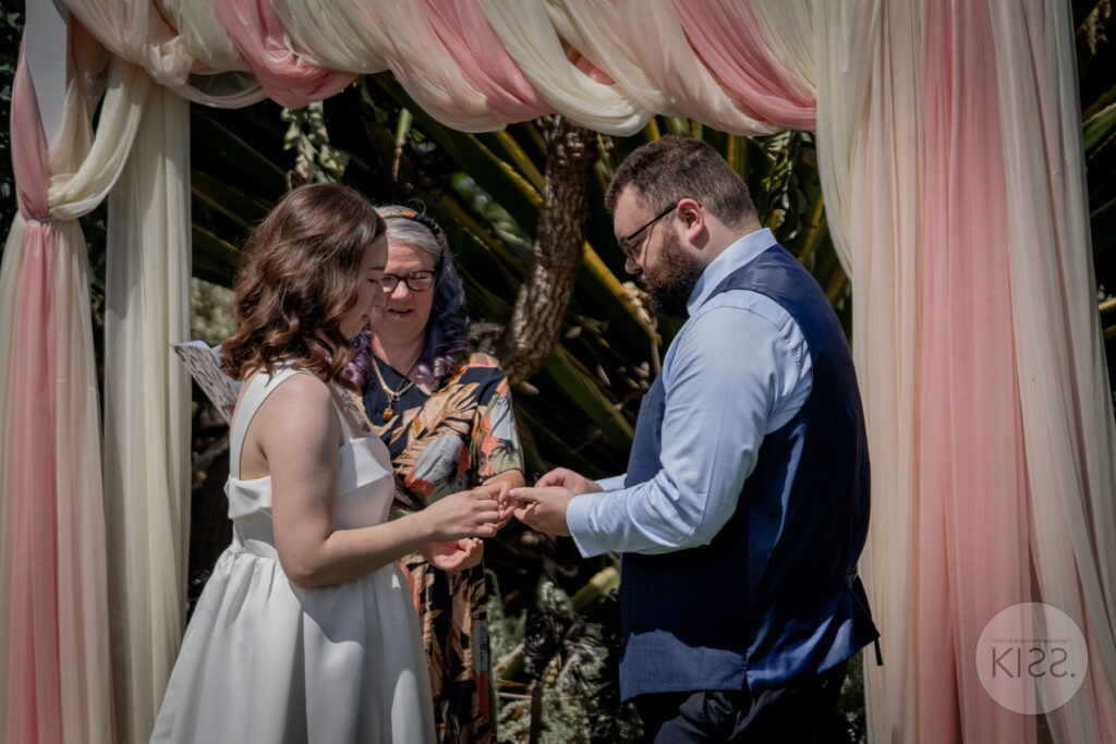 A couple exchanging vows beneath a draped wedding arbour
