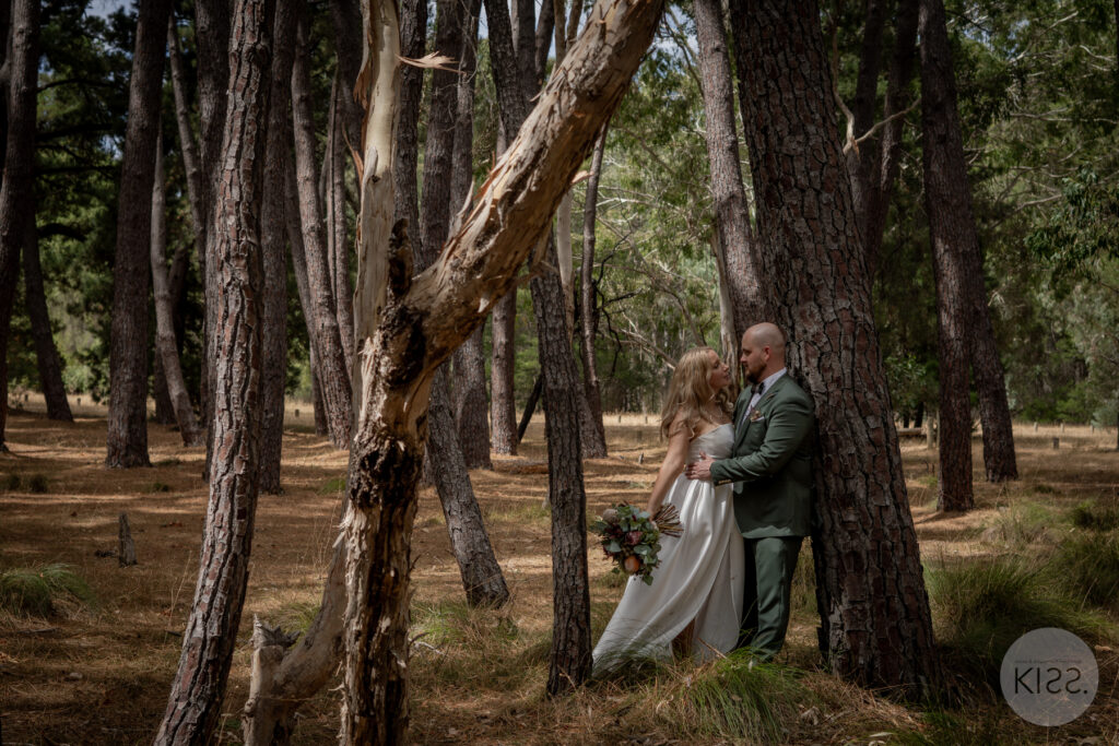 A wedding couple embracing among tall forest trees