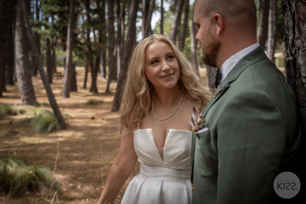 A wedding couple smiling together in the forest