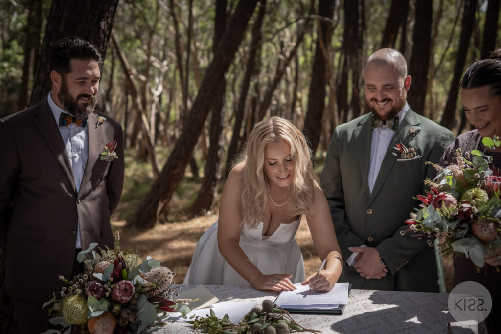 A bride signing the marriage register at a forest wedding