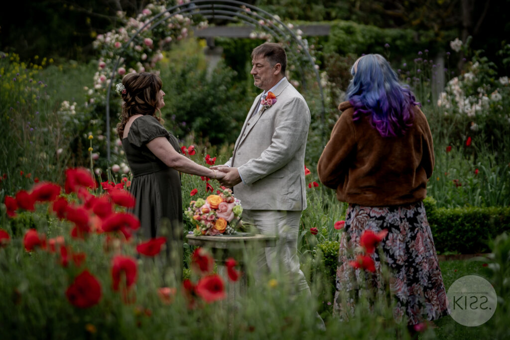 A couple exchanging vows among flowers in a garden setting
