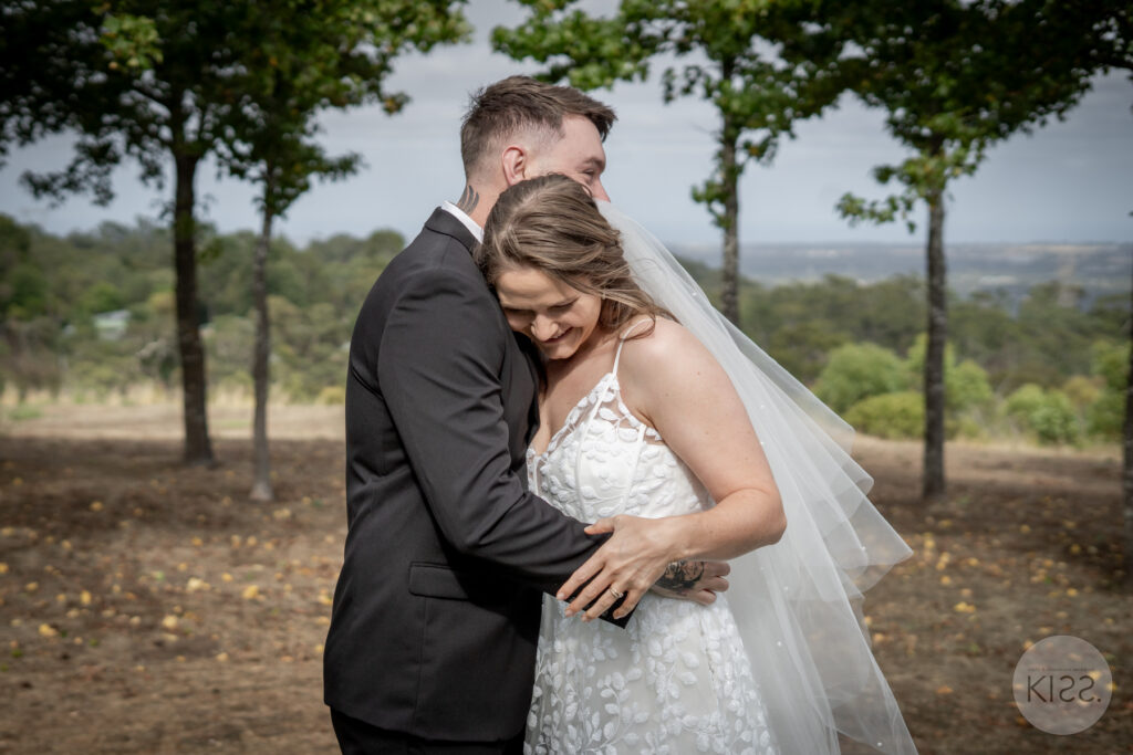 A groom embracing his bride beneath a tree