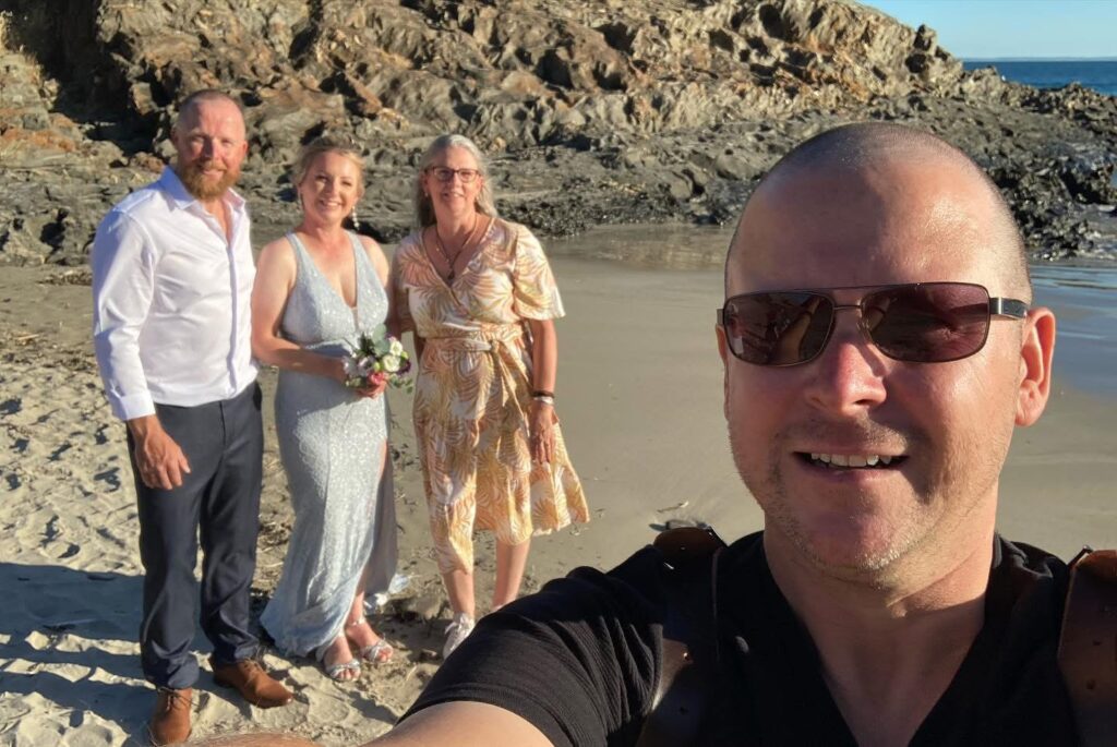 A KISS team member taking a selfie with a wedding couple and celebrant on the coast