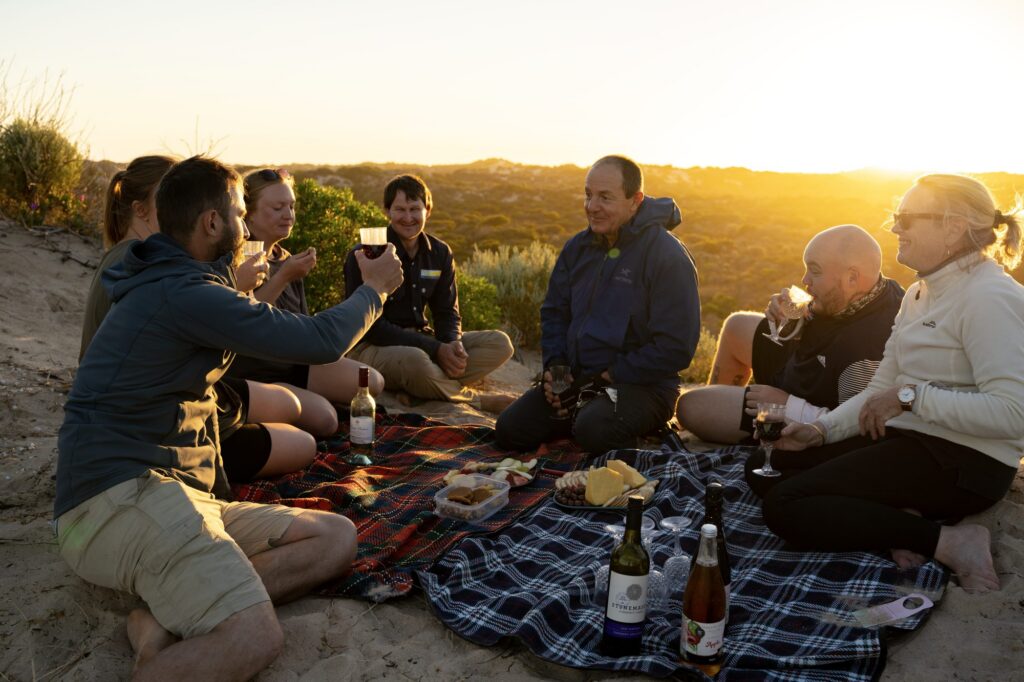 Visitors sharing a sunset picnic during a Canoe the Coorong experience.