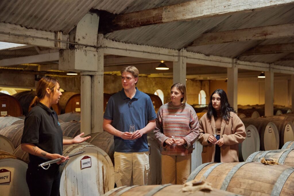 Visitors tasting wine beside barrels at Seppeltsfield Winery