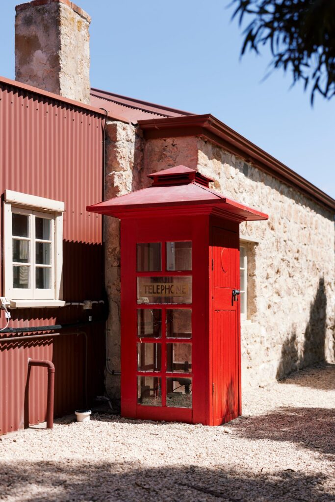 Red telephone box beside a stone building in Inneston Historic Township.
