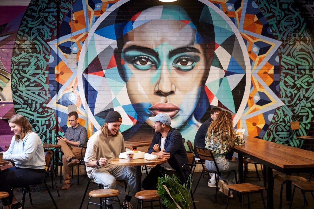 Visitors seated beneath a colourful mural at Adelaide Central Market.