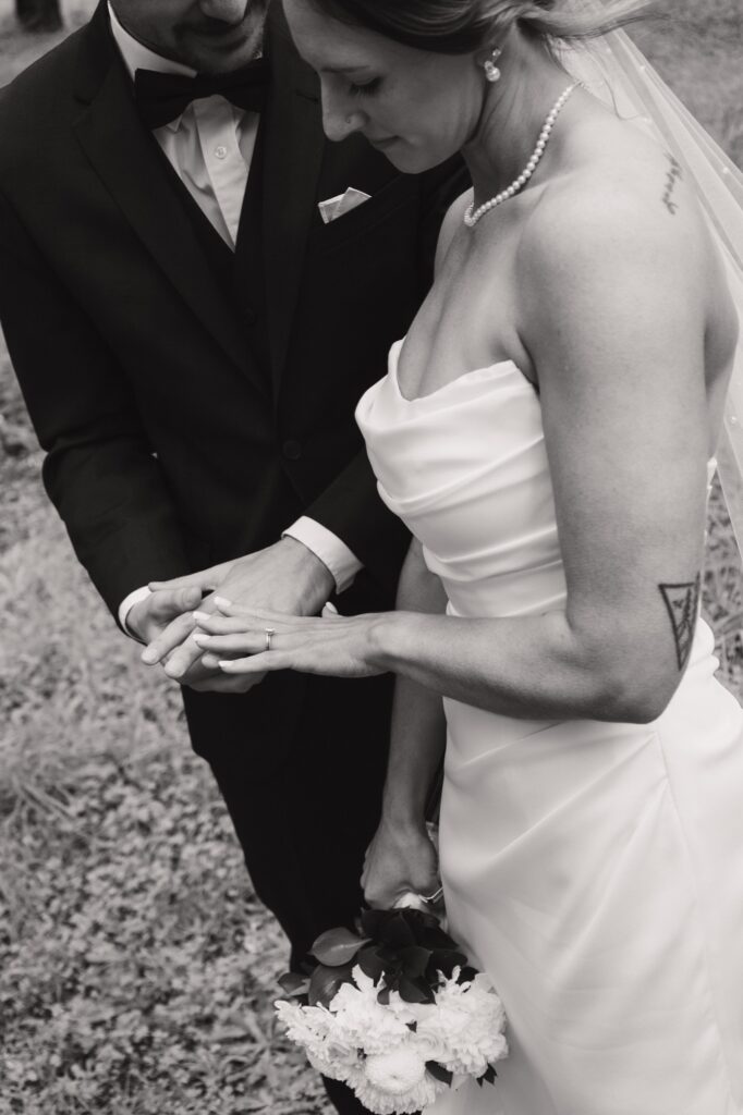 A black-and-white detail of hands and wedding rings