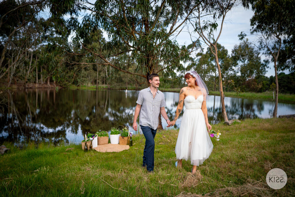 A couple walking beside the pond in a vineyard setting