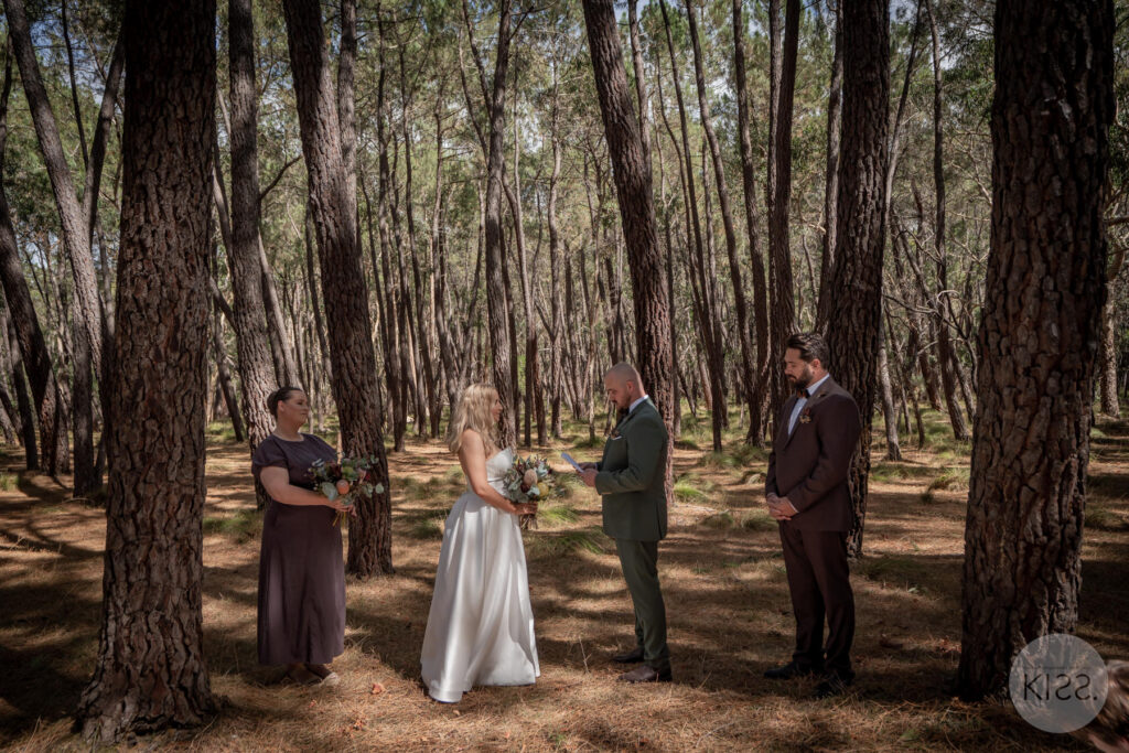 A wedding ceremony among tall forest trees at Rocky Creek Hut