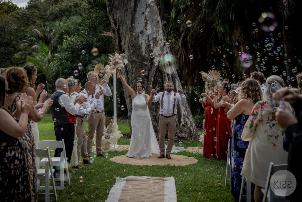 A newly married couple walking through bubbles at Adelaide Botanic Garden