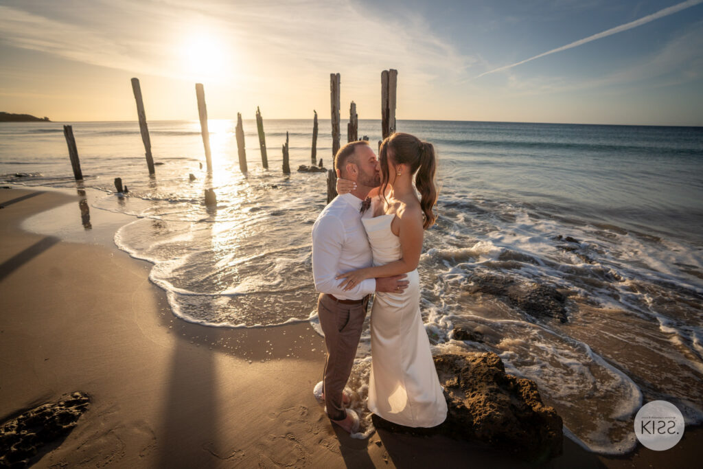 A newly married couple beside the water at sunset at Port Willunga