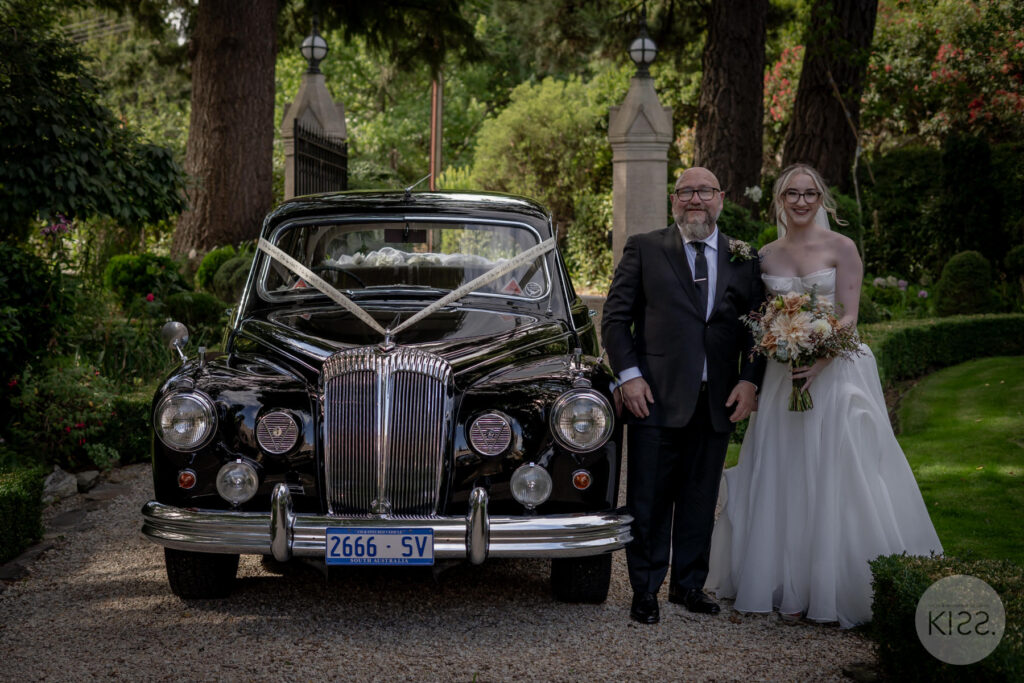 A wedding couple beside a vintage car at Thorngrove Manor