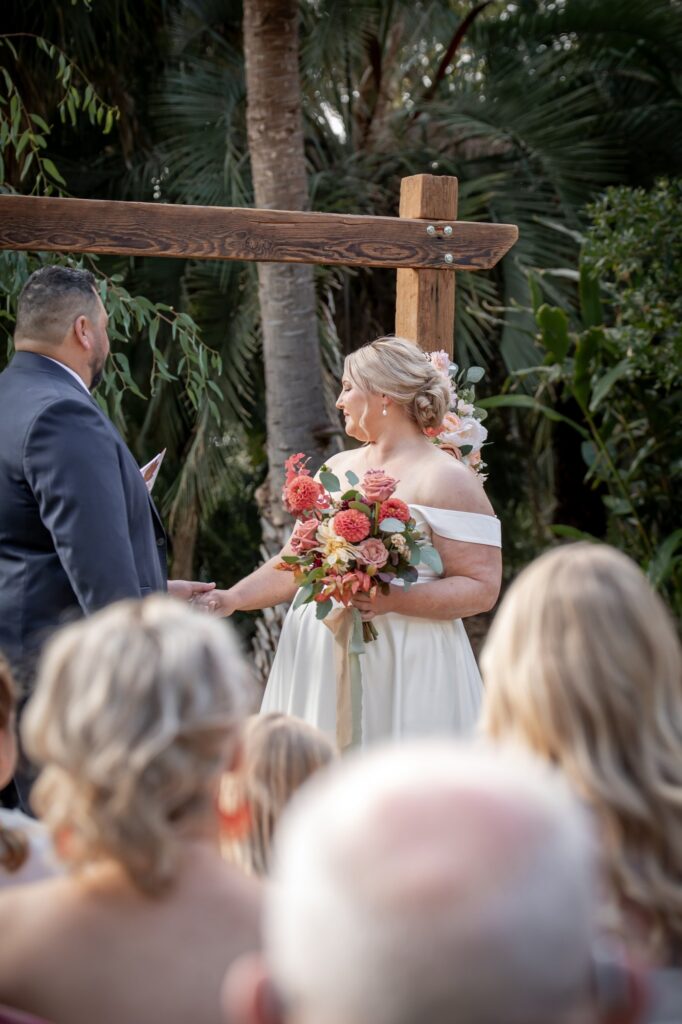 A bride holding a colourful bouquet during vows at Adelaide Botanic Garden