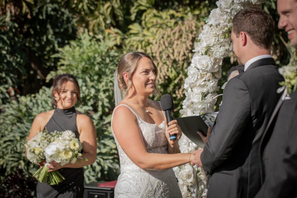 A bride smiling at her partner during their garden wedding vows