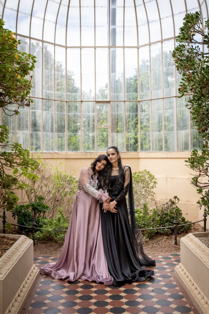 A wedding couple embracing inside a light-filled glasshouse