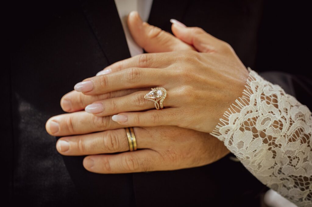 Wedding rings on joined hands with lace sleeve details