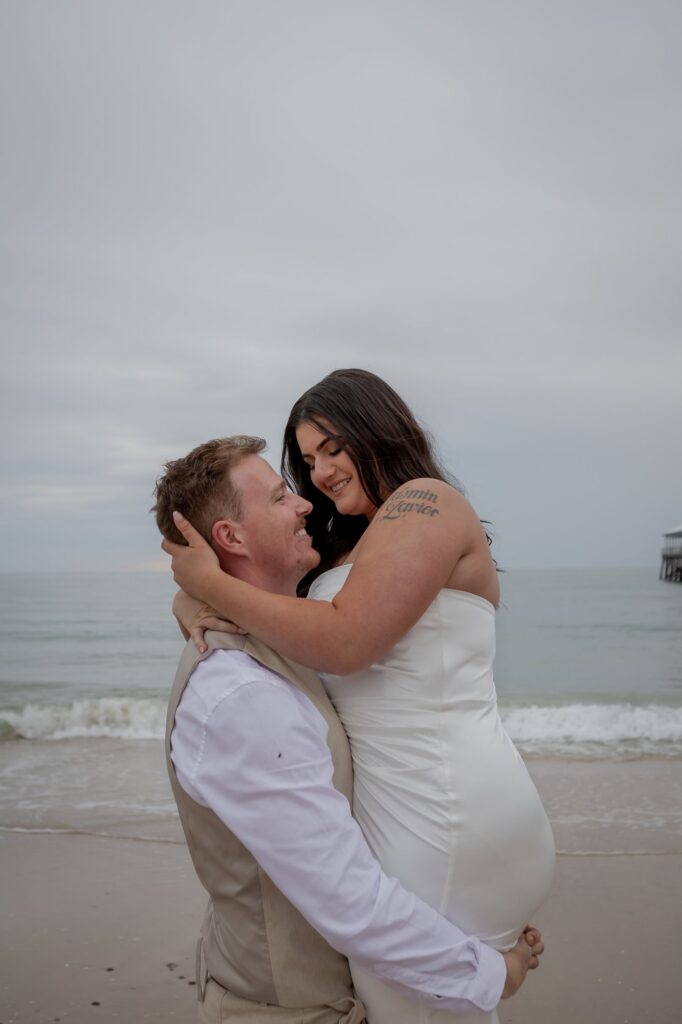 A newly married couple embracing on the beach at Glenelg