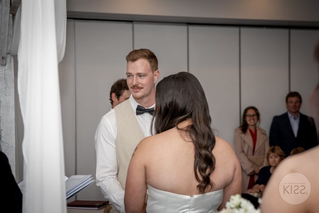 A couple facing each other during an indoor wedding ceremony in Glenelg